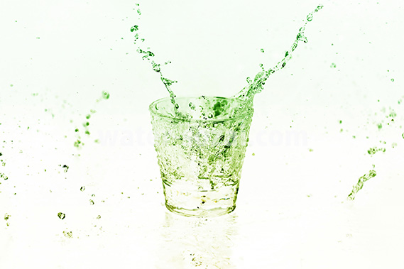 緑色に着色されたロックグラスと水が散布する写真・フォト素材データ