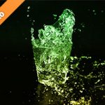 緑色に着色されたロックグラスの水が弾ける写真・フォト素材