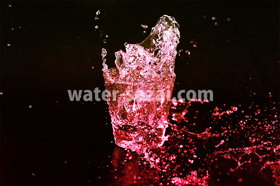 赤色に着色されたロックグラスの水が弾ける写真・フォト素材