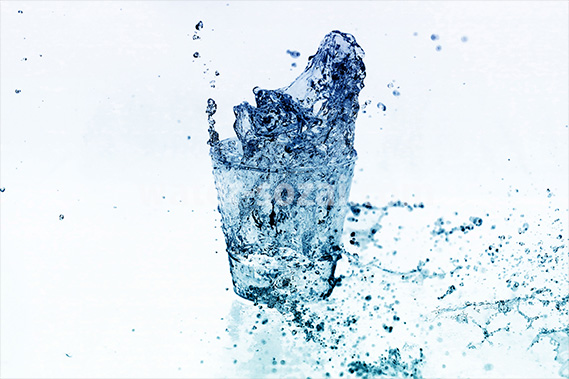 白背景の青色に着色されたロックグラスの水が弾ける写真・フォト素材データ