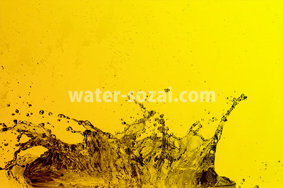 黄色背景の水が弾ける写真・フォト