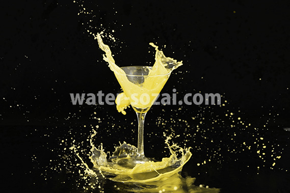 カクテルグラスと黄色い液体が弾ける写真・フォト素材