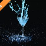 カクテルグラスの上で青い液体が跳ねる写真・フォト素材