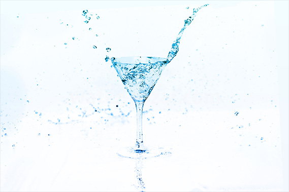 青く透き通るカクテルグラスと水が弾ける写真・フォト素材