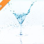 青く透き通るカクテルグラスと水が弾ける写真・フォト素材