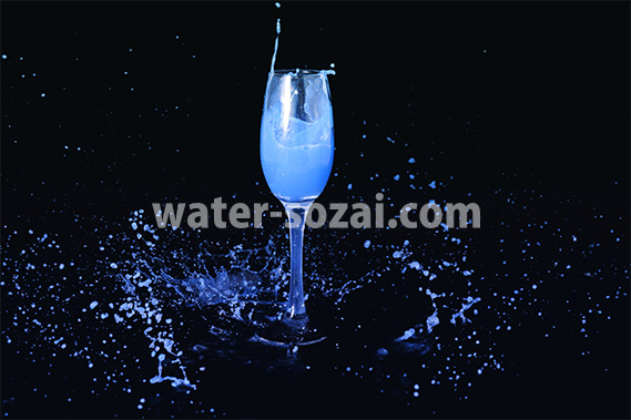 シャンパングラスと青い液体が飛び散る写真・フォト素材