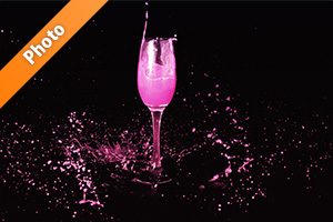シャンパングラスとピンクの液体が飛び散る写真・フォト素材