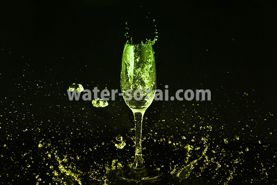 シャンパングラスと黄緑の液体が散布する写真・フォト素材