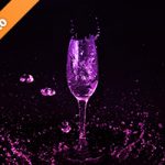 シャンパングラスとピンク・紫の液体が散布する写真・フォト素材