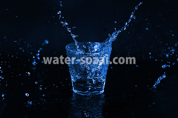 青く着色されたロックグラスと水が散布する写真・フォト素材