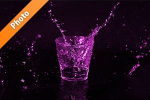 紫色に着色されたロックグラスと水が散布する写真・フォト素材