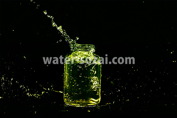 緑色に着色されたビンと水が弾ける写真・フォト素材