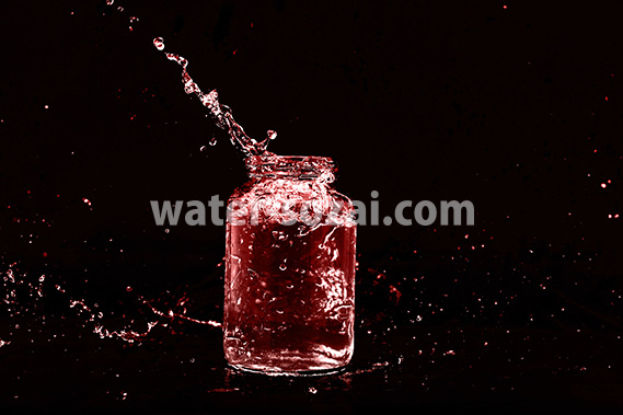 赤色に着色されたビンと水が弾ける写真・フォト素材