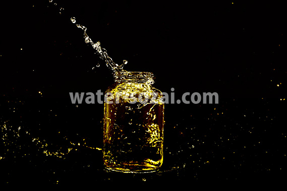 黄色に着色されたビンと水が弾ける写真・フォト素材