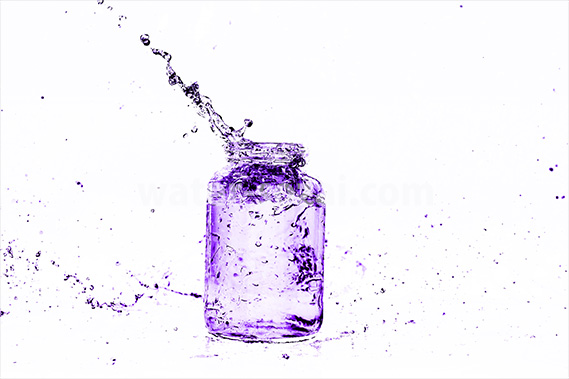 紫色に着色されたビンと水が弾ける写真・フォト素材