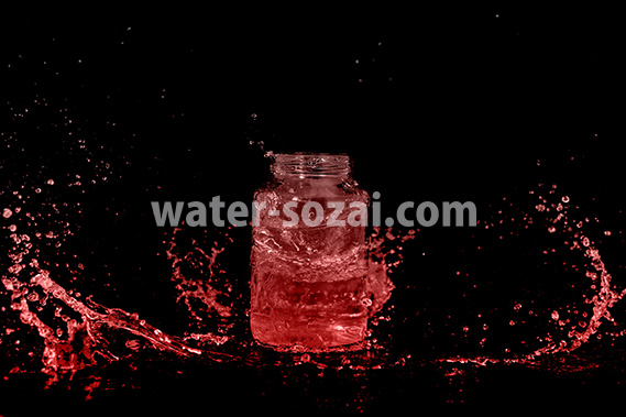 赤く着色されたビンと水が散布する写真・フォト素材