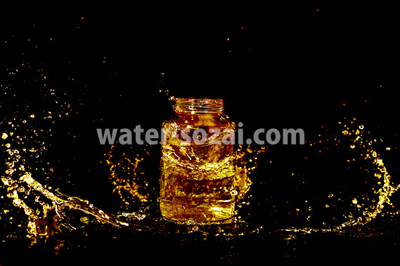 ゴールドカラーに着色されたビンと水が散布する写真・フォト素材