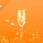 オレンジ色背景のシャンパングラスと水が飛び散る写真・フォト素材