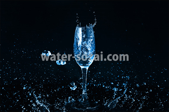 青く着色されたのシャンパングラスと水が飛び散る写真・フォト素材