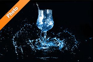 青く着色されたワイングラスと水が散布する写真・フォト素材