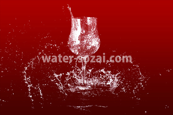 赤い背景のワイングラスと水が散布する写真・フォト素材