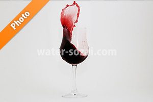 グラス上で赤ワインが跳ね上がる写真・フォト