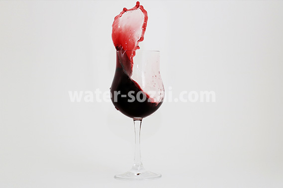グラス上で赤ワインが跳ね上がる写真・フォト