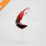 グラスと曲線を描く赤ワインの写真・フォト