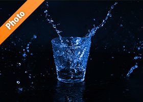青く着色されたロックグラスと水が散布する写真・フォト素材