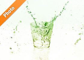 緑色に着色されたロックグラスと水が散布する写真・フォト素材データ