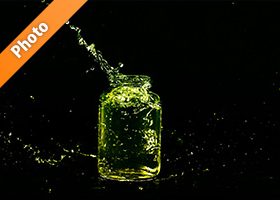 緑色に着色されたビンと水が弾ける写真・フォト素材