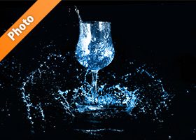 青く着色されたワイングラスと水が散布する写真・フォト素材