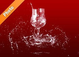 赤い背景のワイングラスと水が散布する写真・フォト素材