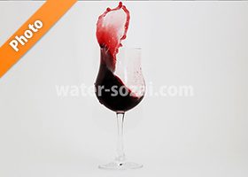 グラス上で赤ワインが跳ね上がる写真・フォト